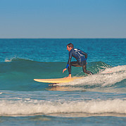 surfstudent toont goede balans en techniek terwijl hij een kleine golf surft