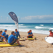 instructeur Peter toont en bespreekt het surfboard op het strand tijdens de lesuitleg