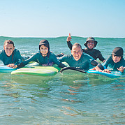 lachende familie poseert samen op het strand na een geslaagde surfdag met kinderen