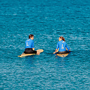 surfstudent zit op zijn board in de line-up en observeert de golven om de juiste te kiezen