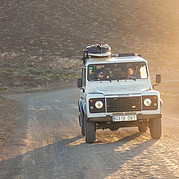 land rover defender geparkeerd aan het strand, klaar om surfers naar afgelegen surfspots te brengen