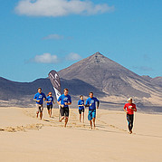 deelnemers van de surfcursus joggen over het strand om op te warmen voor de les