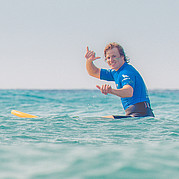 blije surfer maakt het “hang loose” handgebaar na een geslaagde surfsessie