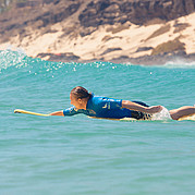 surfer peddelt het water in vanaf een zwemtrap, klaar voor de surfsessie