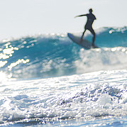 surfer klimt langs de wand van de golf omhoog richting de top om een manoeuvre uit te voeren
